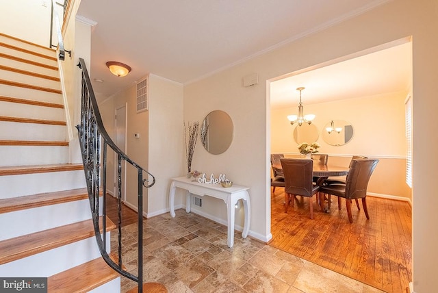 entrance foyer with baseboards, stairs, ornamental molding, and a chandelier