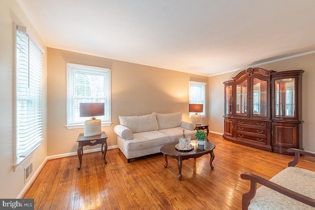 living room featuring light wood finished floors, baseboards, and visible vents