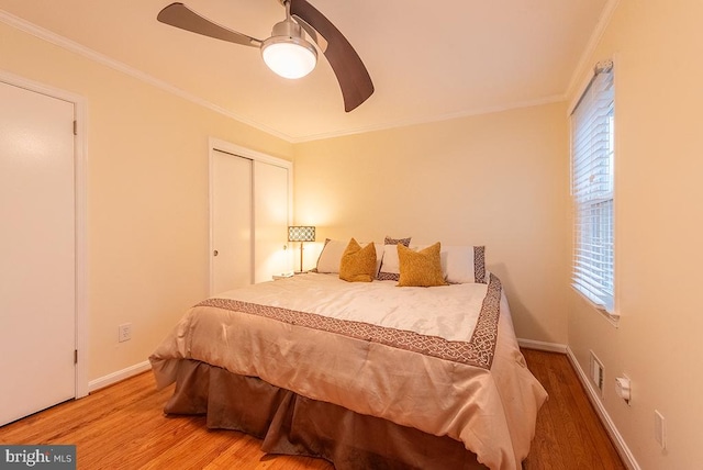 bedroom with baseboards, a closet, wood finished floors, and crown molding