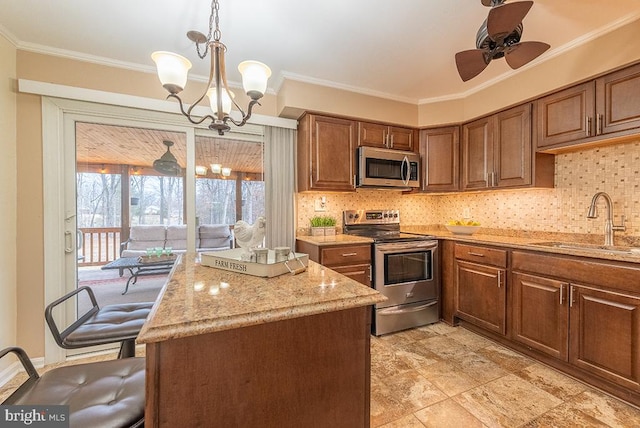 kitchen with crown molding, light stone counters, stainless steel appliances, and a sink