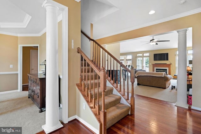 stairway with hardwood / wood-style floors, ornamental molding, ceiling fan, and ornate columns