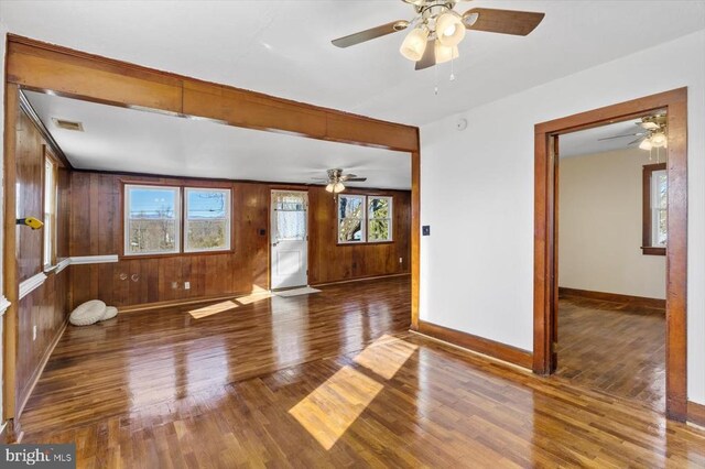 spare room featuring a wealth of natural light, wood-type flooring, and wood walls