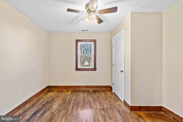 spare room with dark wood-type flooring and ceiling fan