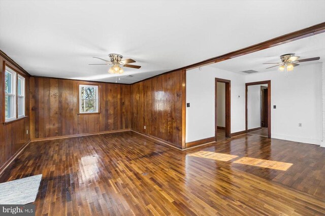 empty room featuring dark wood-type flooring, wooden walls, and ceiling fan