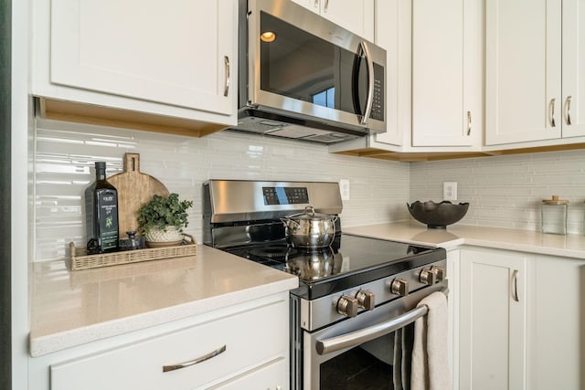 kitchen with white cabinetry, backsplash, and appliances with stainless steel finishes