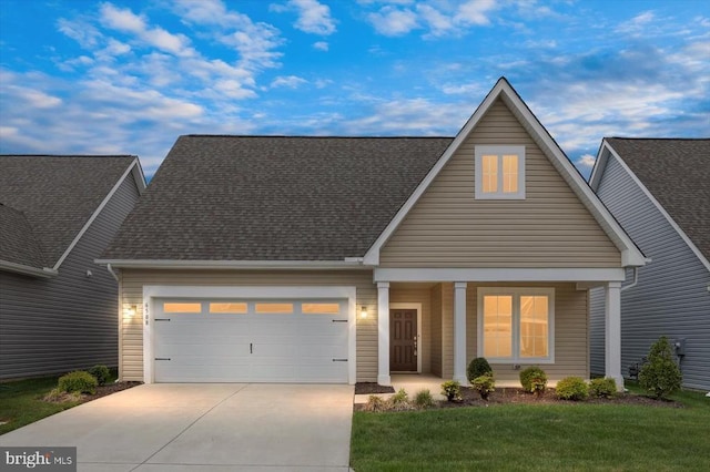 view of front of property featuring roof with shingles, a front lawn, a garage, covered porch, and driveway