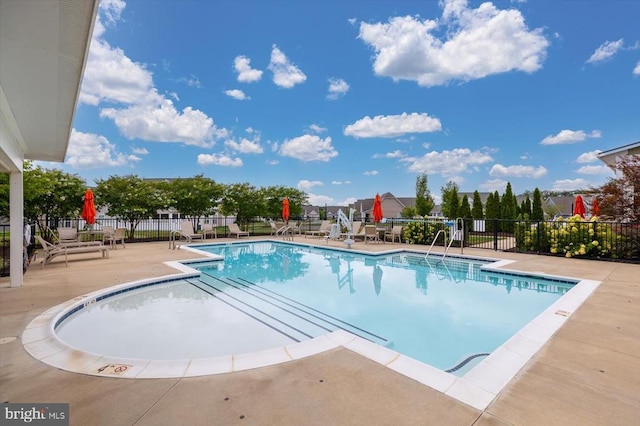 community pool with a patio and fence