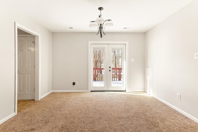 spare room with french doors, a chandelier, and carpet flooring