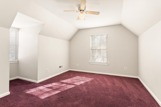 additional living space with dark carpet, ceiling fan, a healthy amount of sunlight, and vaulted ceiling