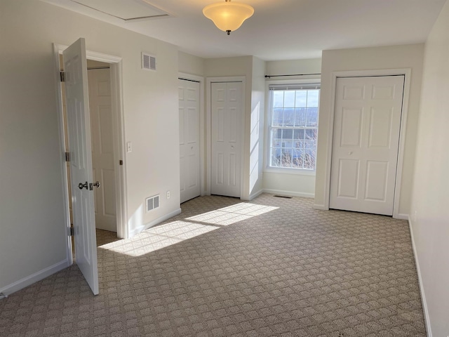 unfurnished bedroom featuring visible vents, baseboards, and two closets