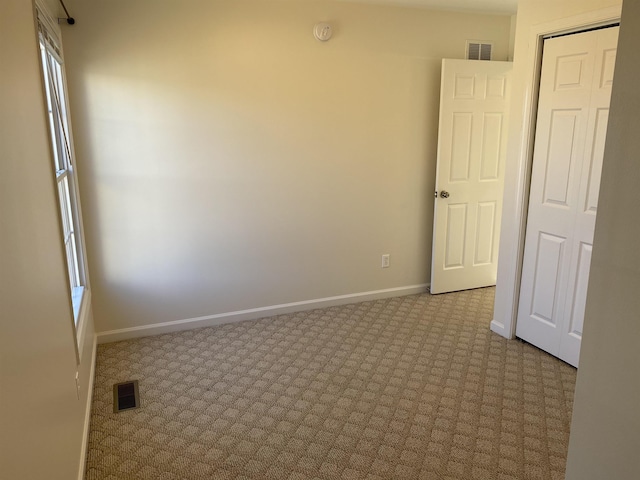 carpeted empty room featuring baseboards and visible vents