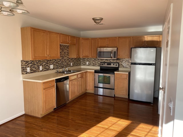 kitchen with dark wood-style floors, a sink, light countertops, appliances with stainless steel finishes, and tasteful backsplash