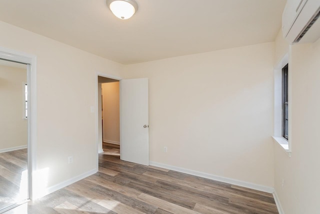 spare room with a wall mounted AC and light wood-type flooring