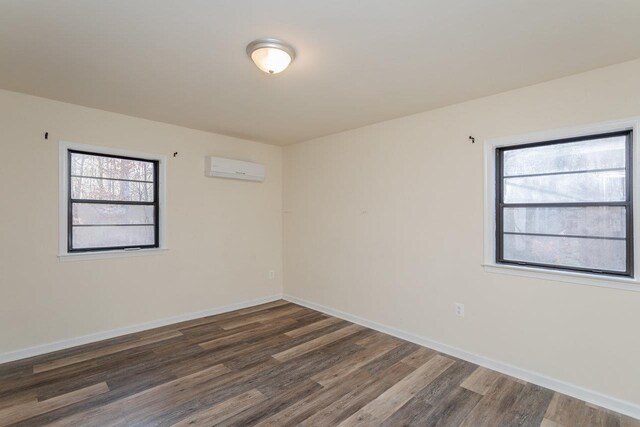 unfurnished room with dark hardwood / wood-style floors and a wall mounted AC