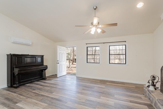 living room with ceiling fan, lofted ceiling, light wood-type flooring, and an AC wall unit