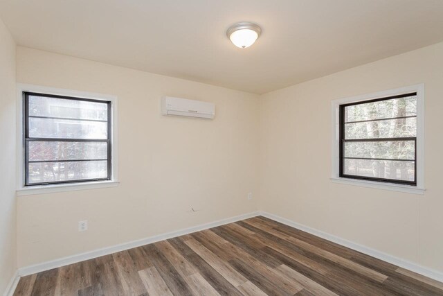 unfurnished room with dark hardwood / wood-style flooring and an AC wall unit