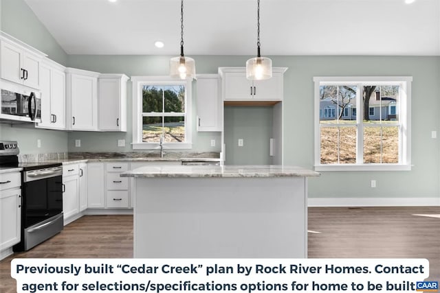 kitchen with light stone counters, stainless steel appliances, hanging light fixtures, and a kitchen island