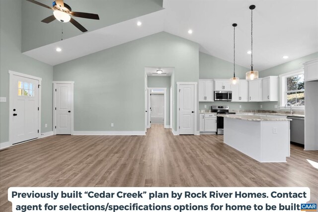 kitchen featuring pendant lighting, stainless steel appliances, a kitchen island, and white cabinets