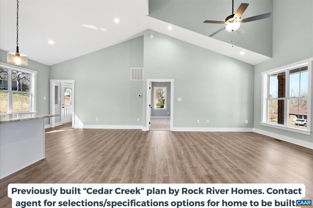 unfurnished living room with hardwood / wood-style floors, a wealth of natural light, and high vaulted ceiling