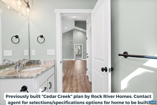 bathroom featuring vanity, lofted ceiling, and wood-type flooring