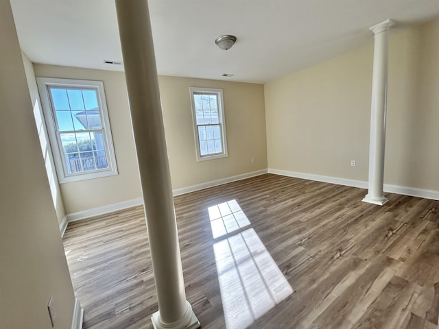 unfurnished room featuring hardwood / wood-style floors and ornate columns