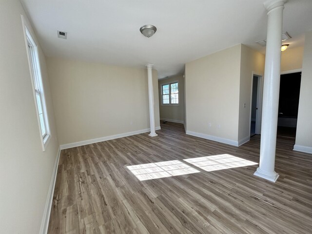 empty room featuring light wood-type flooring and ornate columns