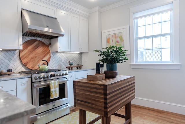 kitchen featuring white cabinets, crown molding, decorative backsplash, gas range, and wall chimney range hood