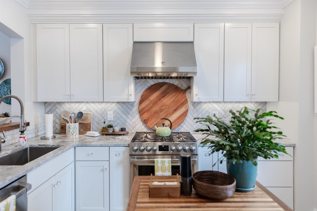 kitchen with wall chimney range hood, sink, white cabinetry, stainless steel appliances, and light stone countertops