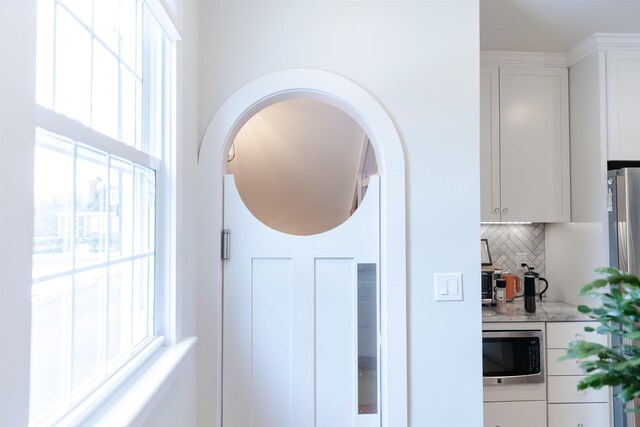 room details with backsplash, stainless steel microwave, and white cabinets