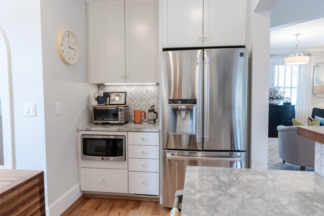 kitchen with light stone counters, appliances with stainless steel finishes, and white cabinets