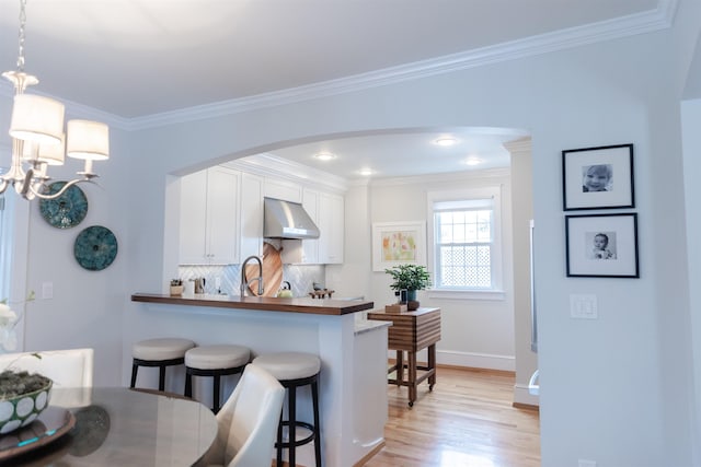 kitchen with a breakfast bar, decorative light fixtures, white cabinetry, decorative backsplash, and kitchen peninsula