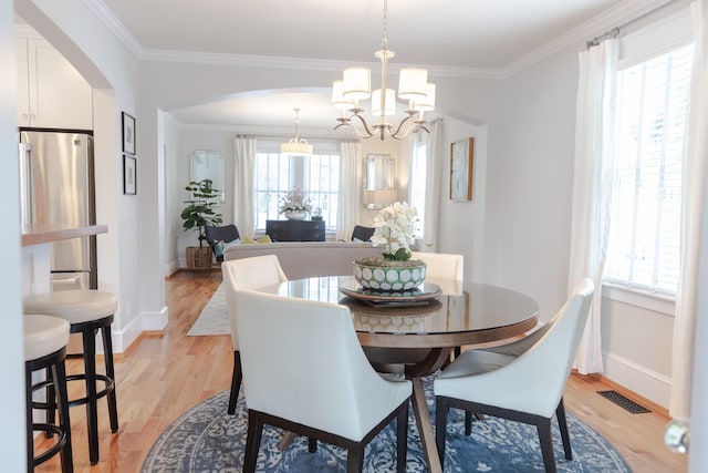 dining space featuring crown molding, a chandelier, and light hardwood / wood-style floors