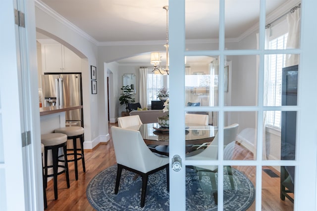 dining area with ornamental molding, hardwood / wood-style floors, and a notable chandelier