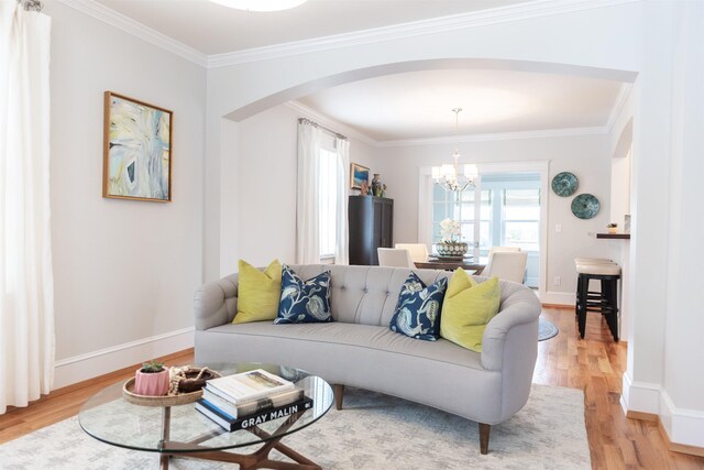 living room featuring ornamental molding, an inviting chandelier, and light hardwood / wood-style floors