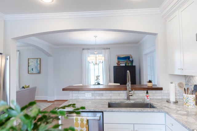 kitchen with pendant lighting, dishwasher, white cabinetry, sink, and light stone counters