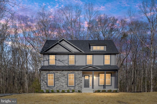 view of front facade featuring a front lawn and a shingled roof