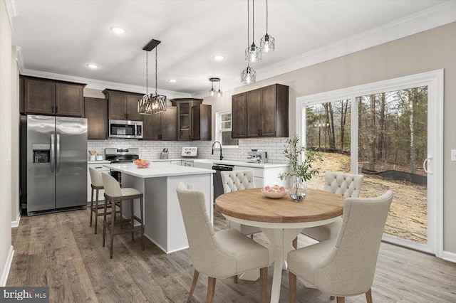 kitchen with stainless steel appliances, ornamental molding, dark brown cabinetry, decorative backsplash, and a kitchen island