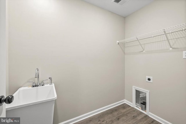 washroom with electric dryer hookup, wood finished floors, and baseboards