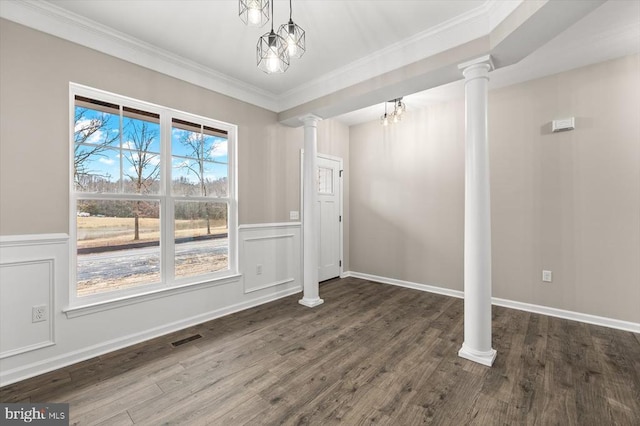 unfurnished dining area with decorative columns, wood finished floors, crown molding, a wainscoted wall, and a chandelier