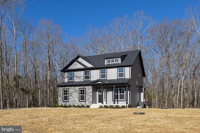 craftsman inspired home featuring covered porch, cooling unit, a front lawn, and stone siding