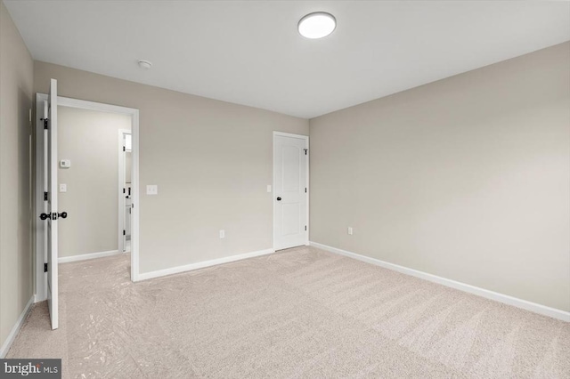 unfurnished room with light carpet and baseboards