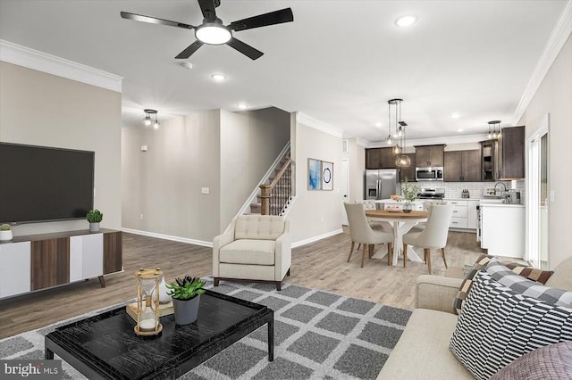 living area featuring crown molding, light wood finished floors, stairway, recessed lighting, and a ceiling fan