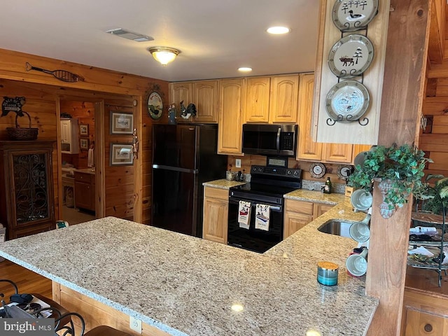 kitchen featuring a peninsula, a sink, visible vents, black appliances, and light stone counters