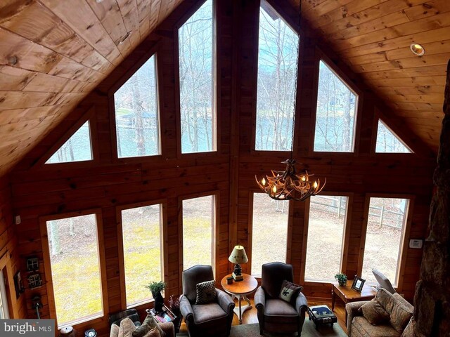 living area featuring wooden walls, an inviting chandelier, high vaulted ceiling, and wooden ceiling