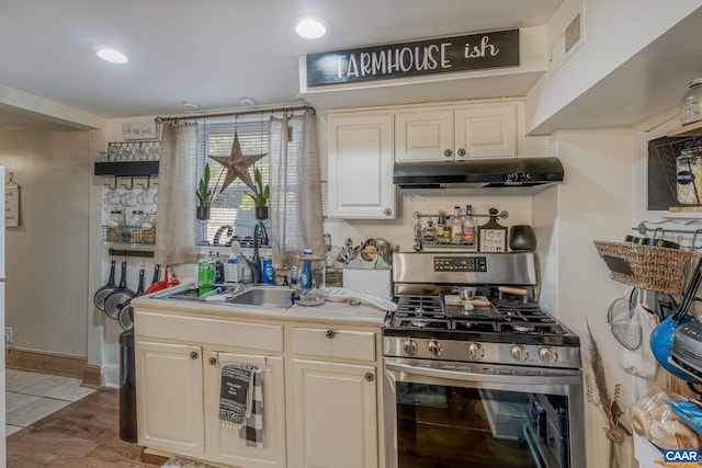 kitchen featuring a sink, visible vents, under cabinet range hood, gas range, and light countertops