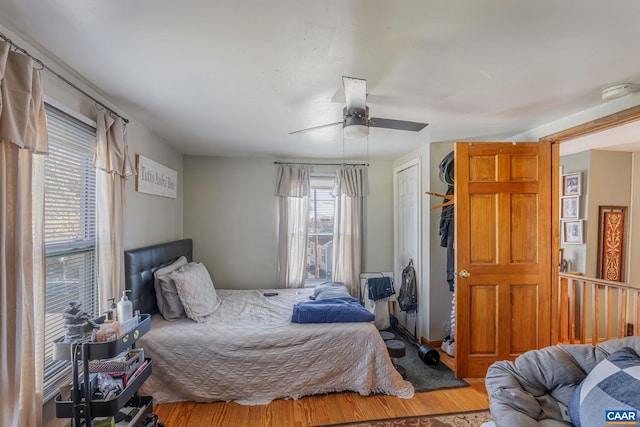 bedroom featuring multiple windows, a closet, ceiling fan, and wood finished floors