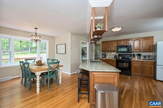 168 Lakeland Ln, Faber, VA 22938 - kitchen featuring black appliances, light wood-style flooring, brown cabinets, decorative light fixtures, and a breakfast bar area
