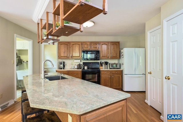 168 Lakeland Ln, Faber, VA 22938 - kitchen with black appliances, light wood-style floors, brown cabinetry, light stone countertops, and decorative backsplash