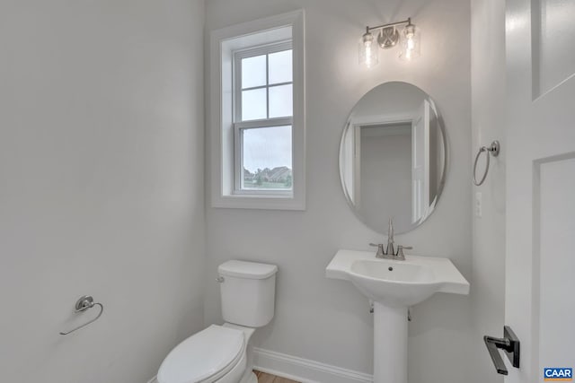 half bath with baseboards and toilet