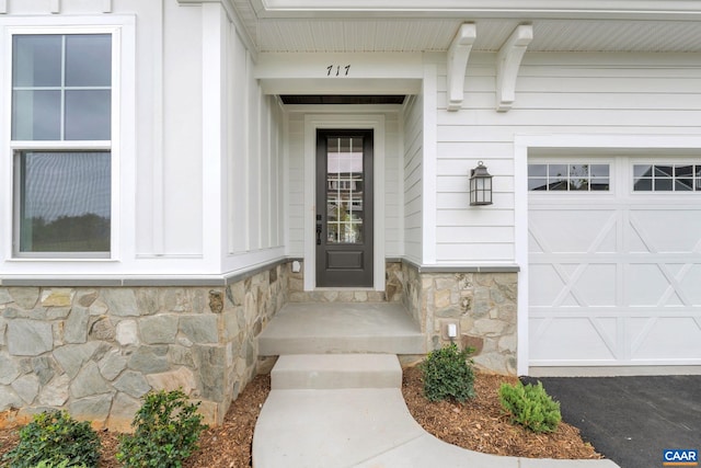 property entrance with a garage and stone siding